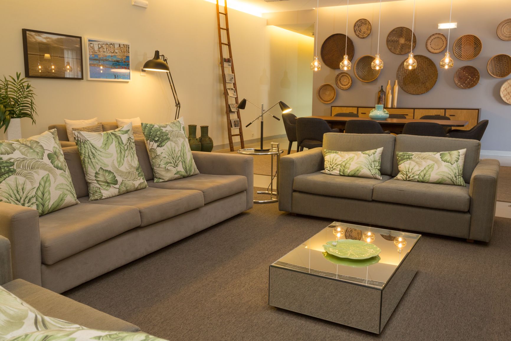 Un salon moderne avec deux canapés gris, une table basse et des éléments de décoration murale, notamment des assiettes et des tableaux encadrés.