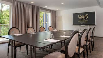 A conference room with a long table, chairs, and a projector screen displaying "Victoria's Residenz-Hotel Saarbrücken".
