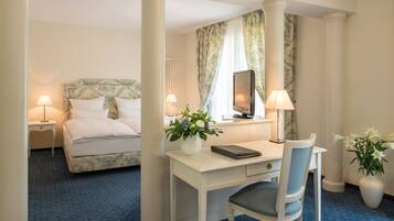 A hotel room with a bed, a desk, a chair, and two lamps.