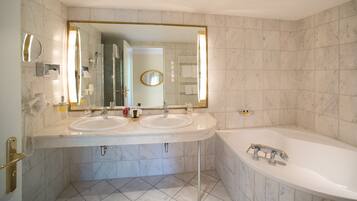 Ein modernes Badezimmer mit zwei Waschbecken, einer großen Badewanne und einem Spiegel mit goldener Rahmung.