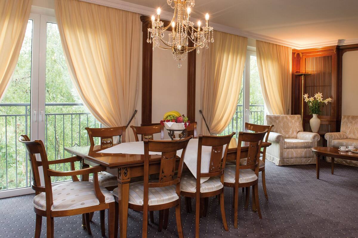 A dining area with a table and chairs, a sofa, and a chandelier.