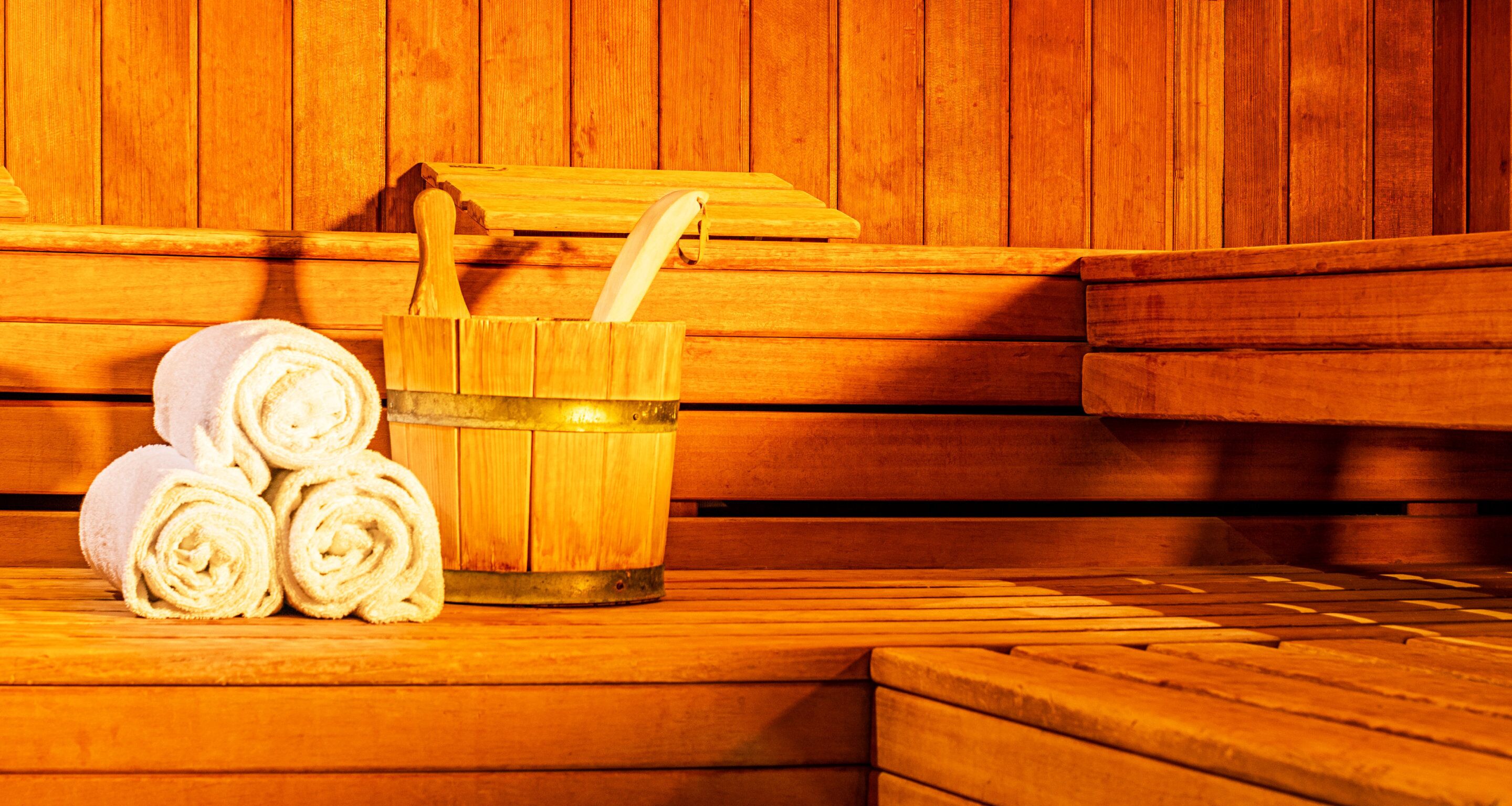 A sauna with wooden benches and a wooden bucket with a brush.