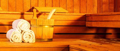 A sauna with wooden benches and a wooden bucket with a brush.