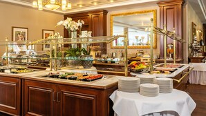 Un espace buffet avec différents postes de service pour les aliments, une vitrine réfrigérée et un miroir.