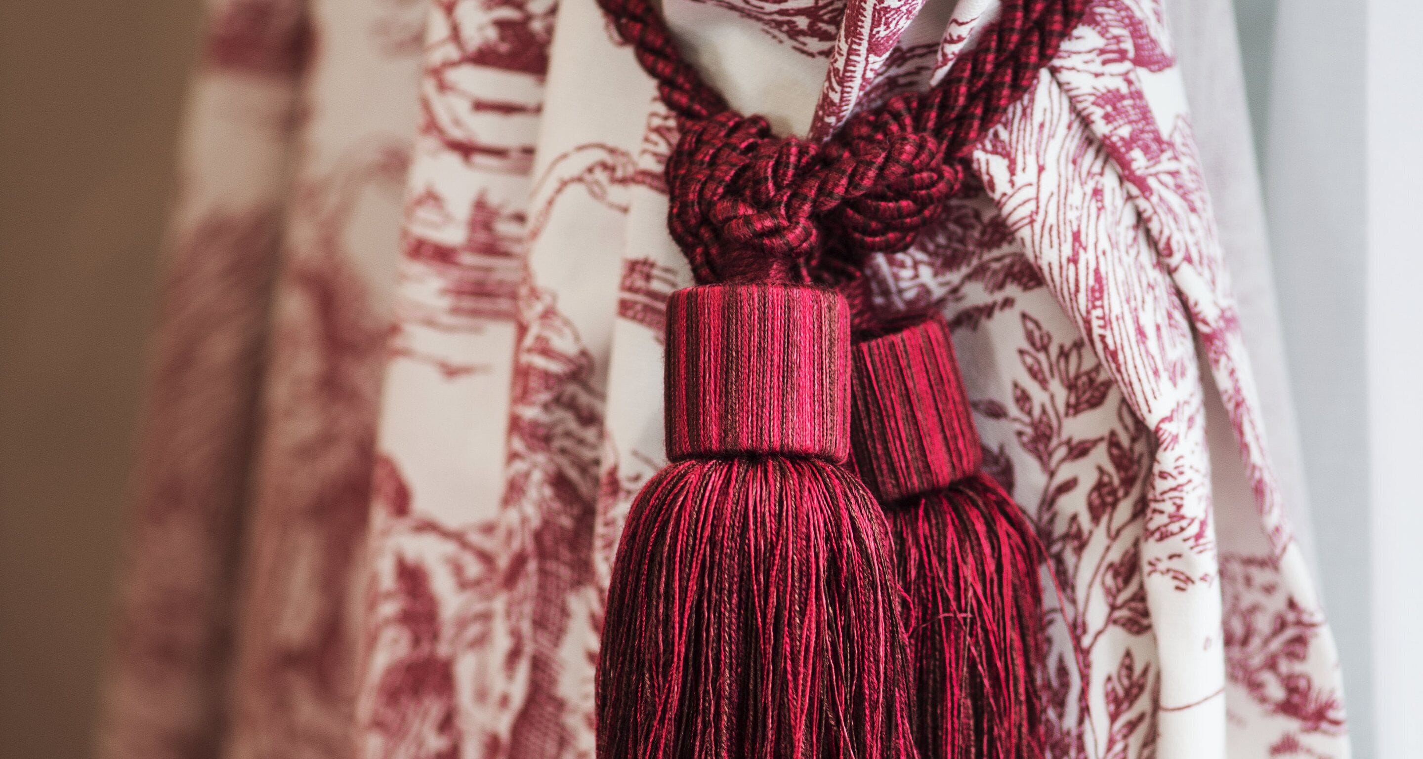 A close-up of a decorative tassel hanging from a curtain with a floral pattern.