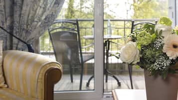 A room with a sofa, a chair, a table, and a potted plant with flowers.