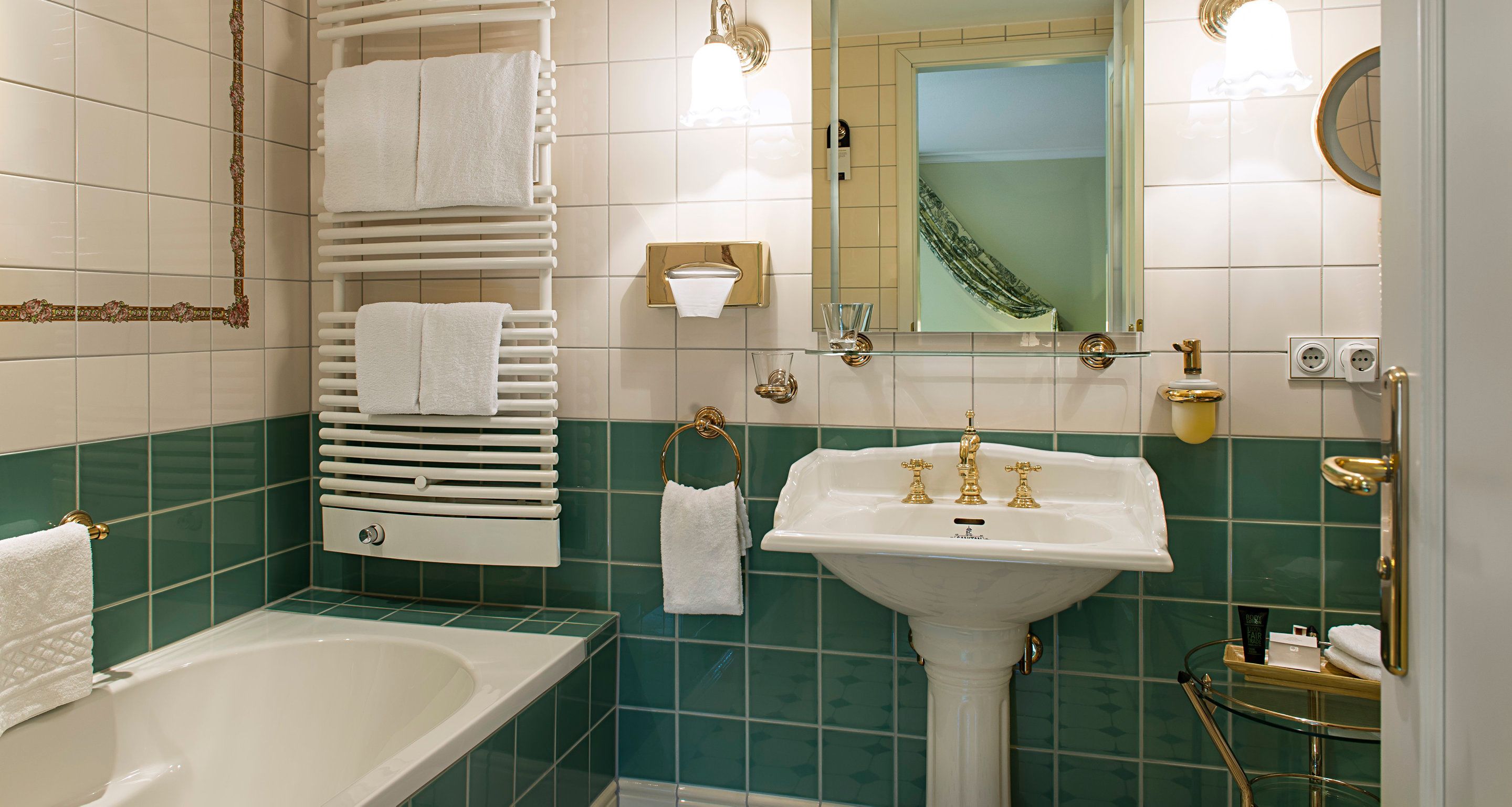 Un baño con bañera, lavamanos y toallero.