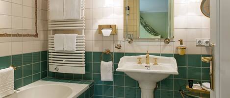 A bathroom with a bathtub, a sink, and a towel rack.