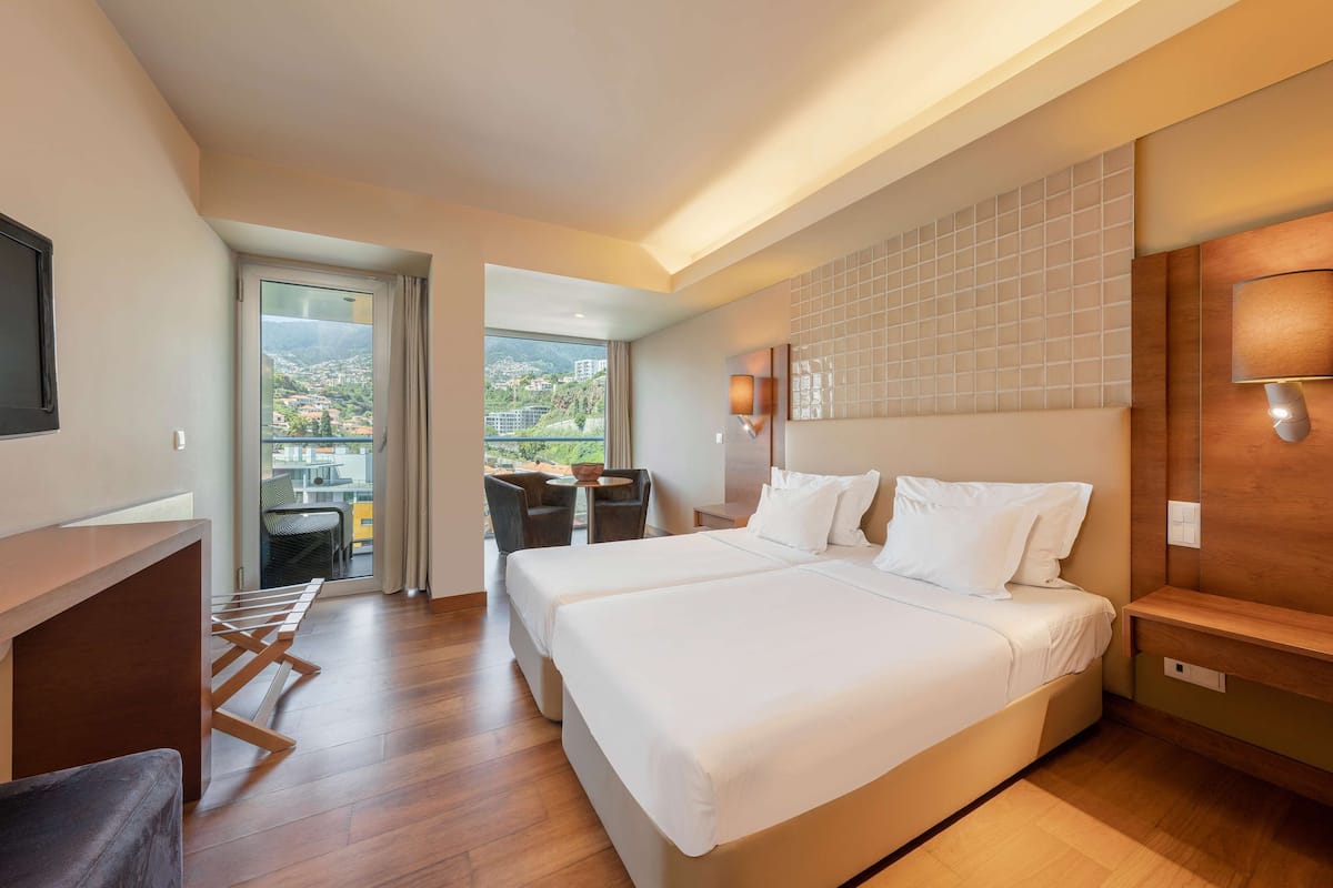 Une chambre d’hôtel avec un grand lit, un bureau et un balcon offrant une vue sur la ville.