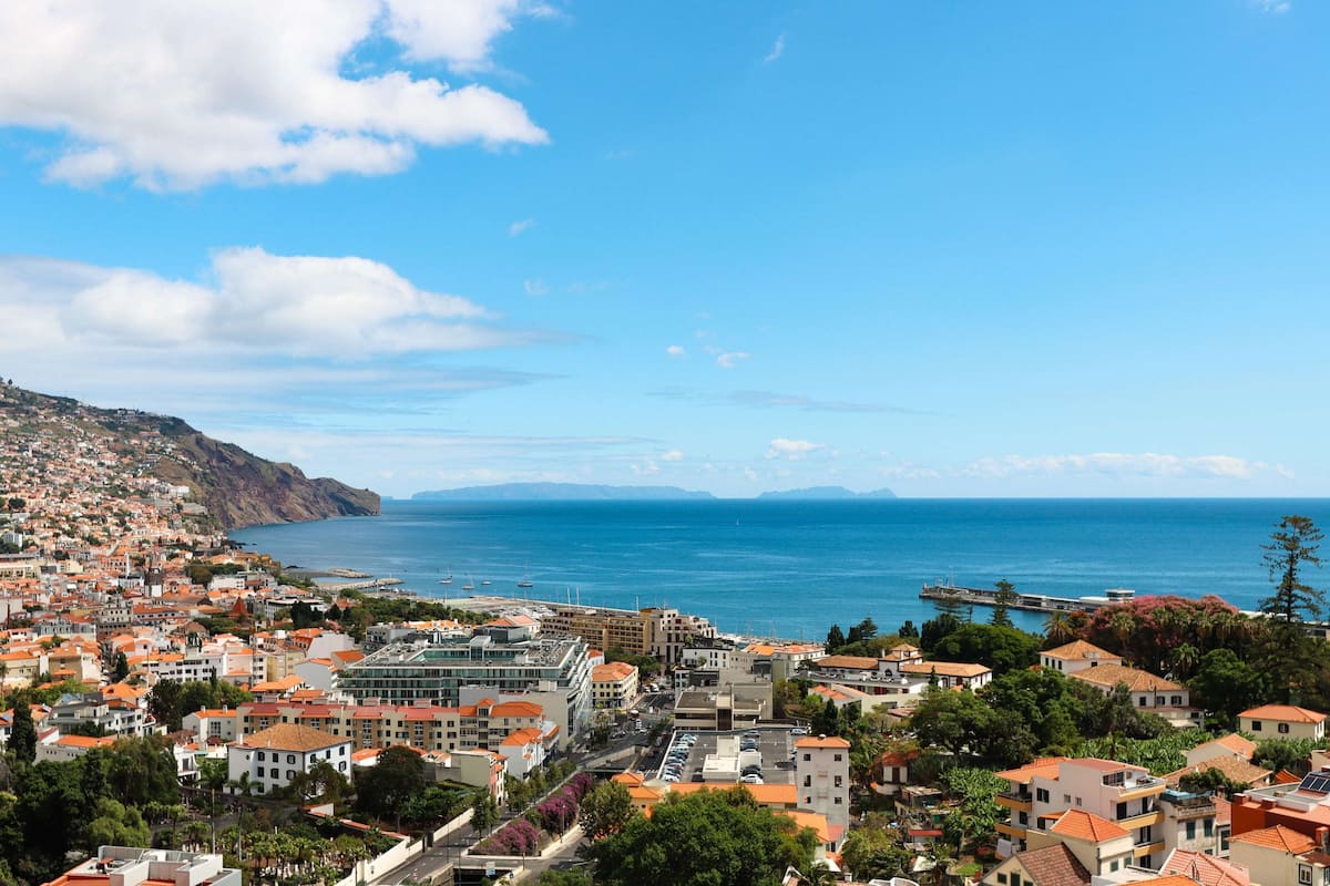 Une ville c ôtière où se côtoient des bâtiments résidentiels et commerciaux, offrant une vue dégagée sur la mer et s’étendant sur un paysage vallonné.