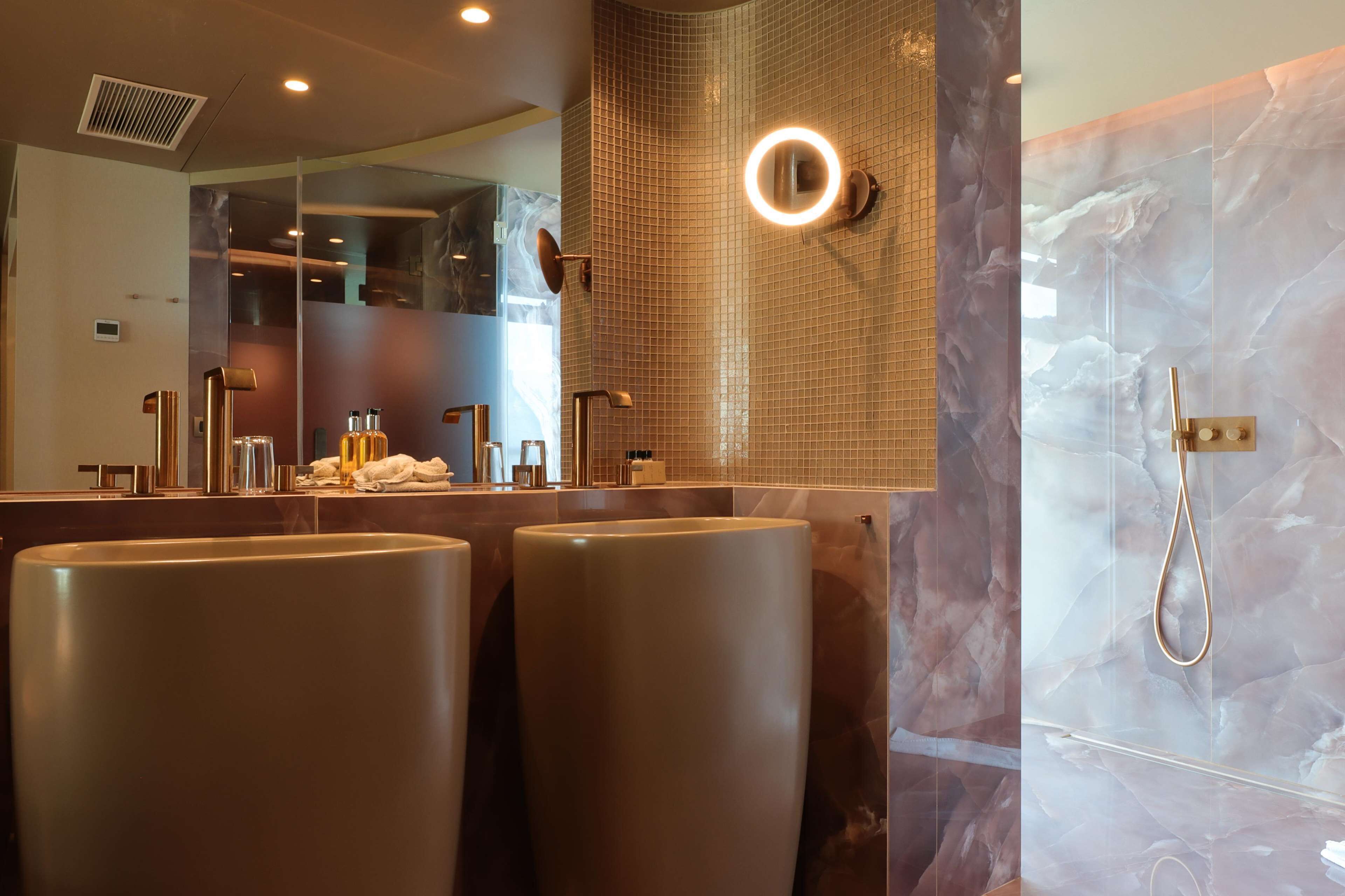 Ein modernes Badezimmer mit zwei Waschbecken, einem großen Spiegel und einer Duschkabine mit Marmorwand.