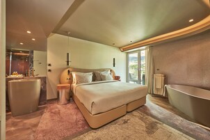 Camera da letto moderna con un letto grande, una vasca idromassaggio integrata e un'ampia finestra con vista sull'esterno.