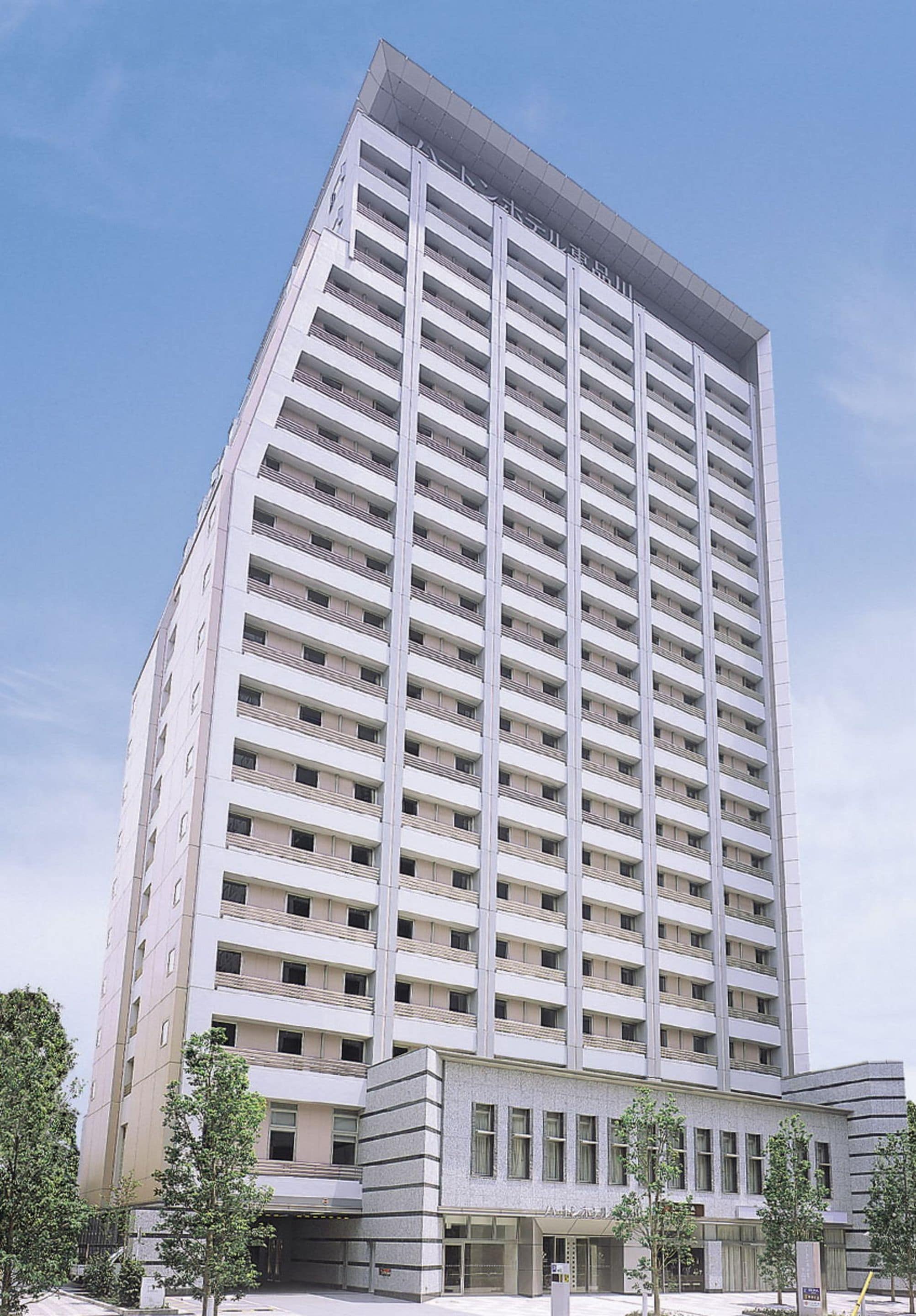 Een hoog, modern hotel met een rechthoekige vorm, meerdere balkons en een plat dak.