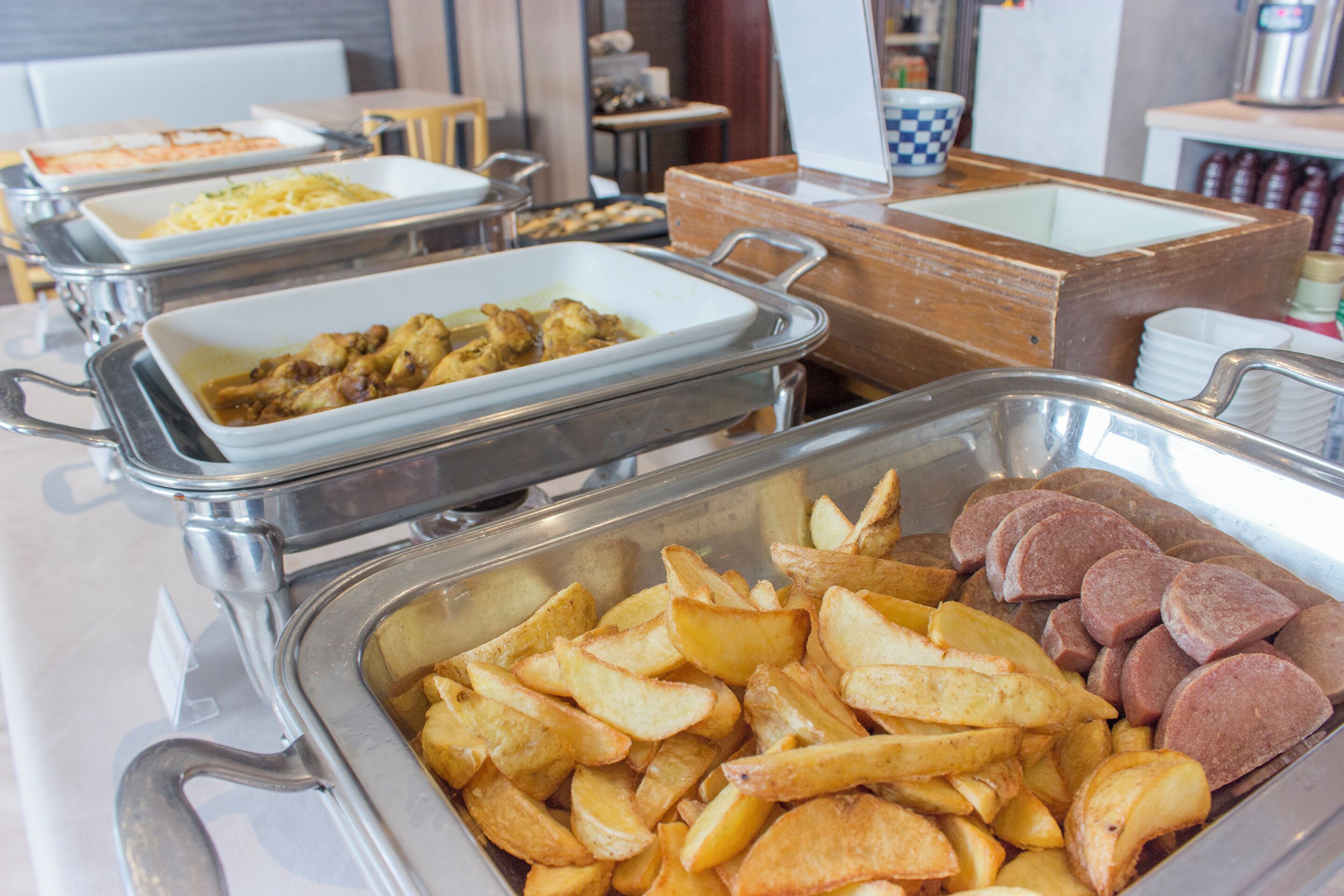 A buffet with various food options including potatoes, meats, and other dishes.