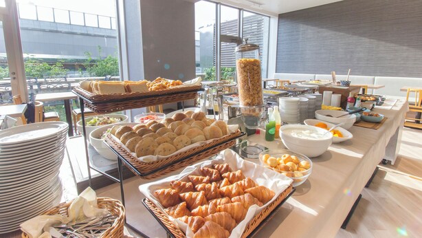 A buffet with various food items and a view of a building outside. - Hearton Hotel Higashishinagawa (Tokyo)