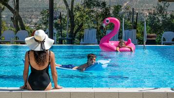 A swimming pool with lounge chairs, a pink flamingo float, and a person in a swimsuit.