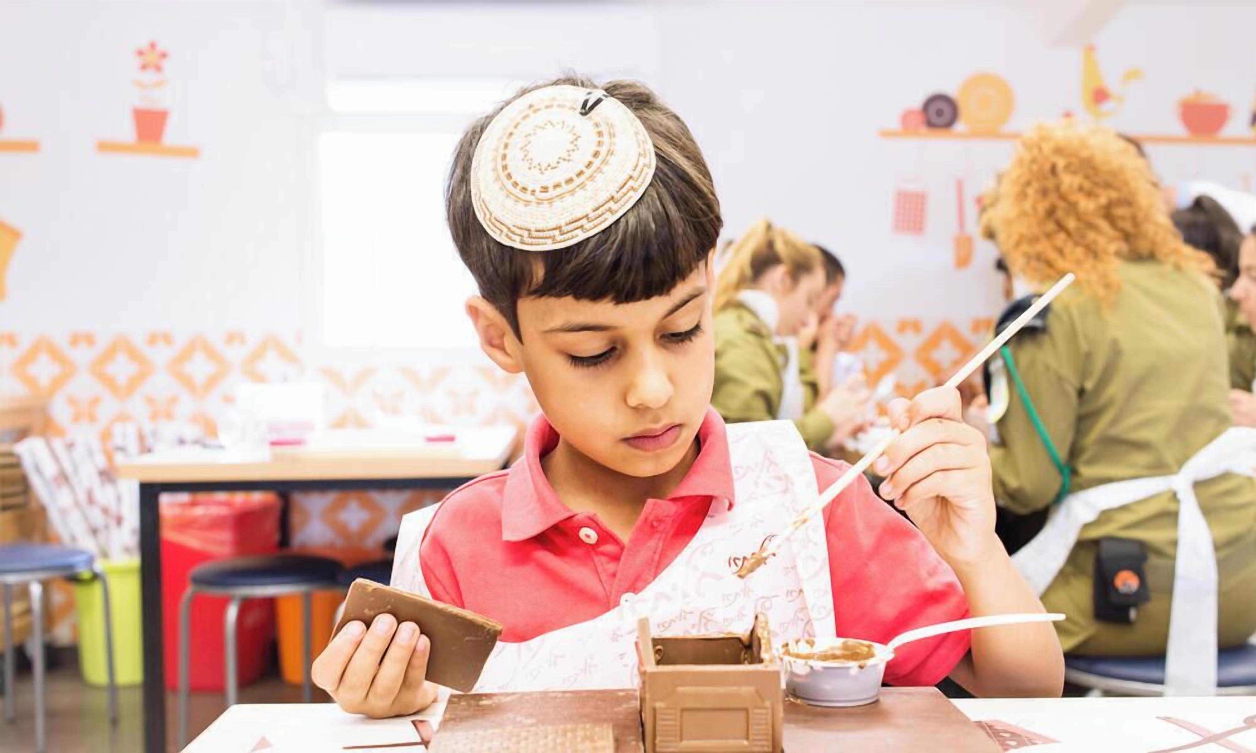 A child seated at a table with a snack, a tablet, and a drink.