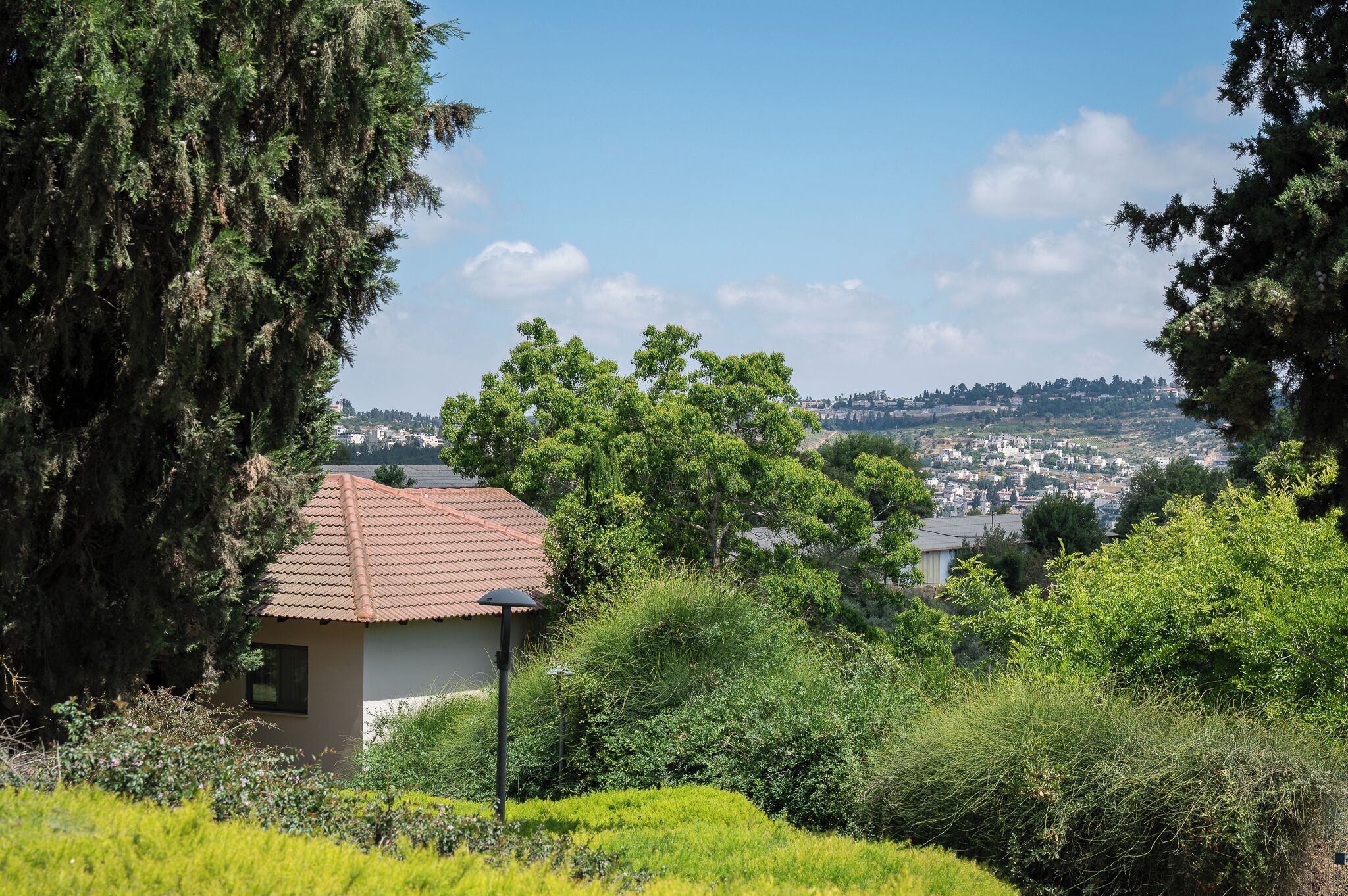 A house with a tiled roof, surrounded by greenery and overlooking a town.