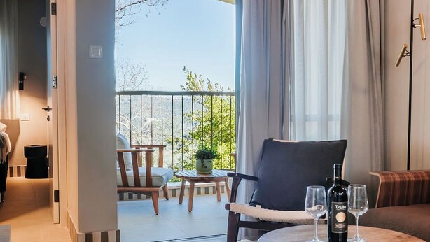 Une chambre moderne avec un balcon, une table ronde avec une bouteille et des verres, et un canapé.