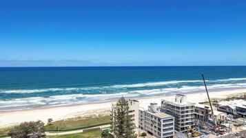 Um hotel à beira-mar com vários andares, vista para a praia e uma grua de construção.