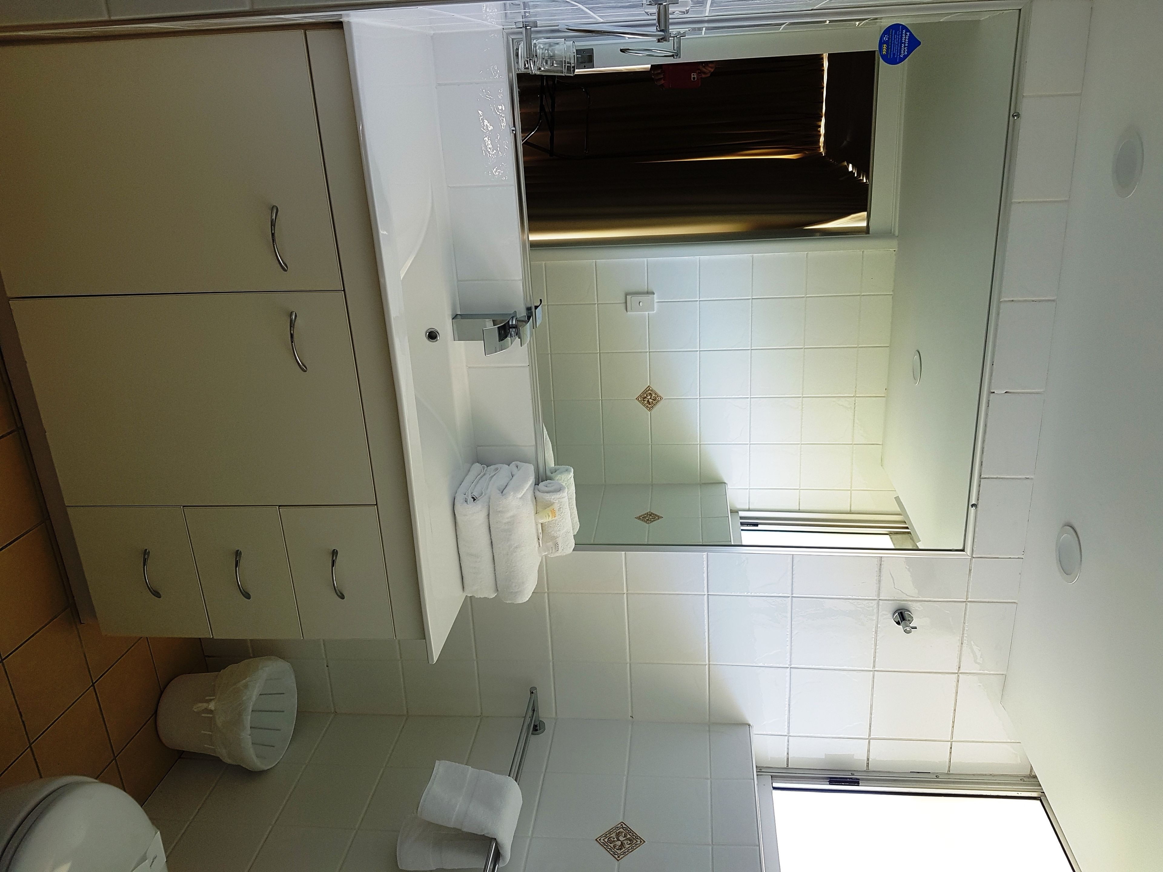 Une salle de bain avec des carreaux blancs, un lavabo avec un miroir et des toilettes.