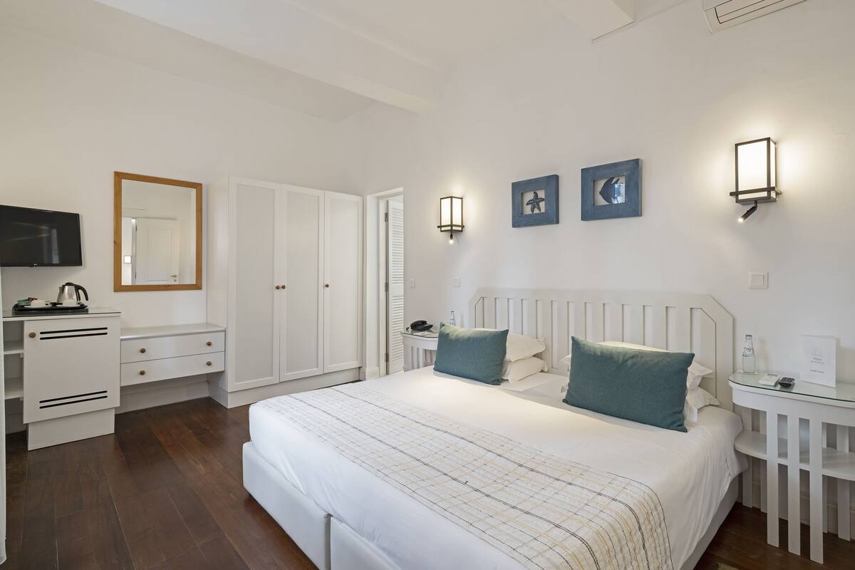 Une chambre à coucher avec un grand lit, une télévision, une armoire et deux lampes fixées au mur.