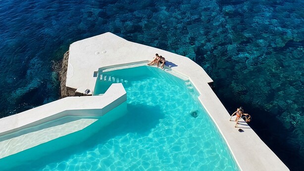 A pool with clear blue water and a view of the ocean.
