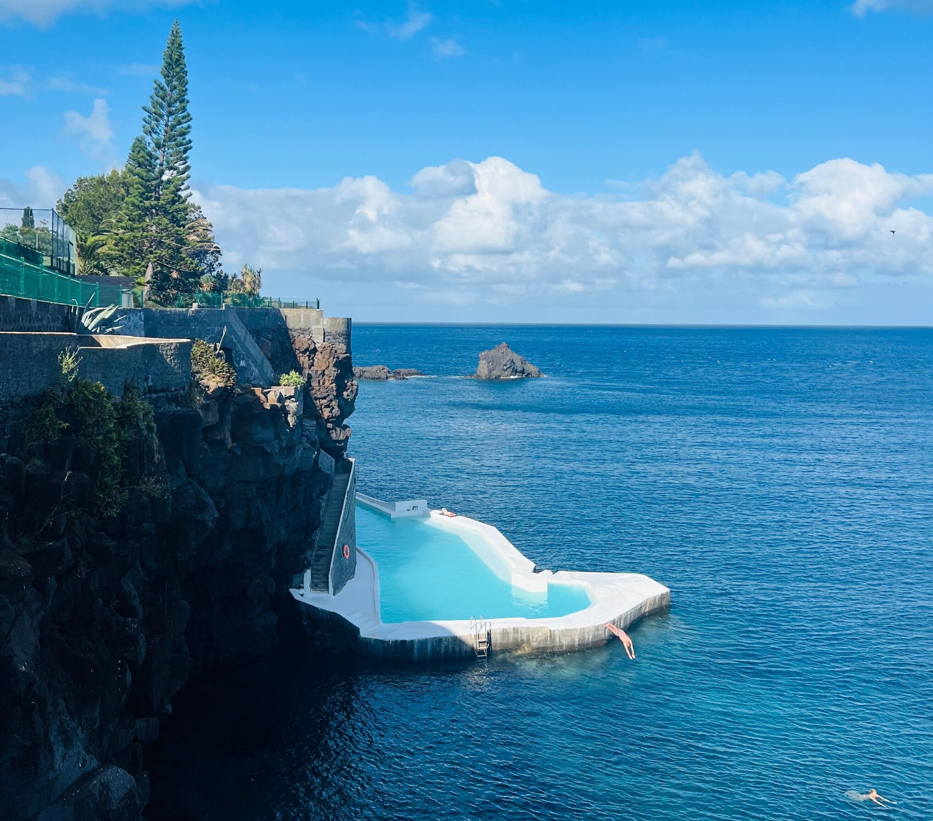 A cliffside pool with a clear view of the ocean and a rocky outcrop.