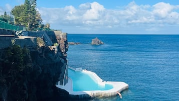 A cliffside pool with a clear view of the ocean and a rocky outcrop.