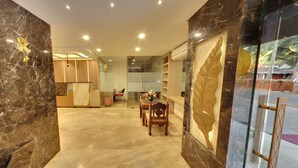A hotel lobby with marble flooring, a reception desk, a dining area with chairs, and a large decorative mirror. - Calangute Grande (Calangute)