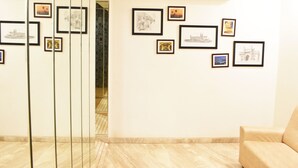 A lobby with framed artwork on the walls, a beige sofa, and a marble floor. - Calangute Grande (Calangute)