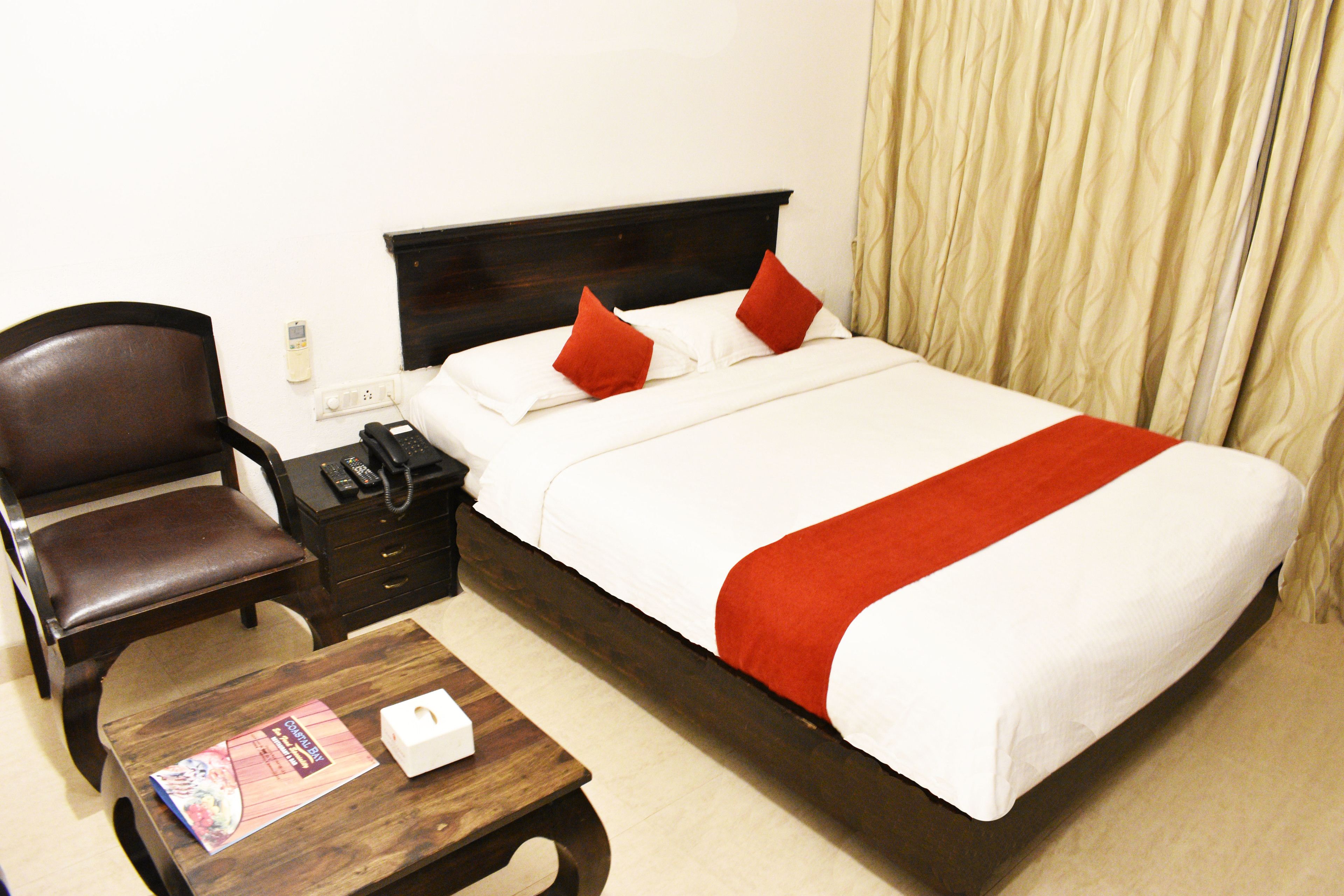 A hotel room with a bed, a chair, a nightstand, and a table.