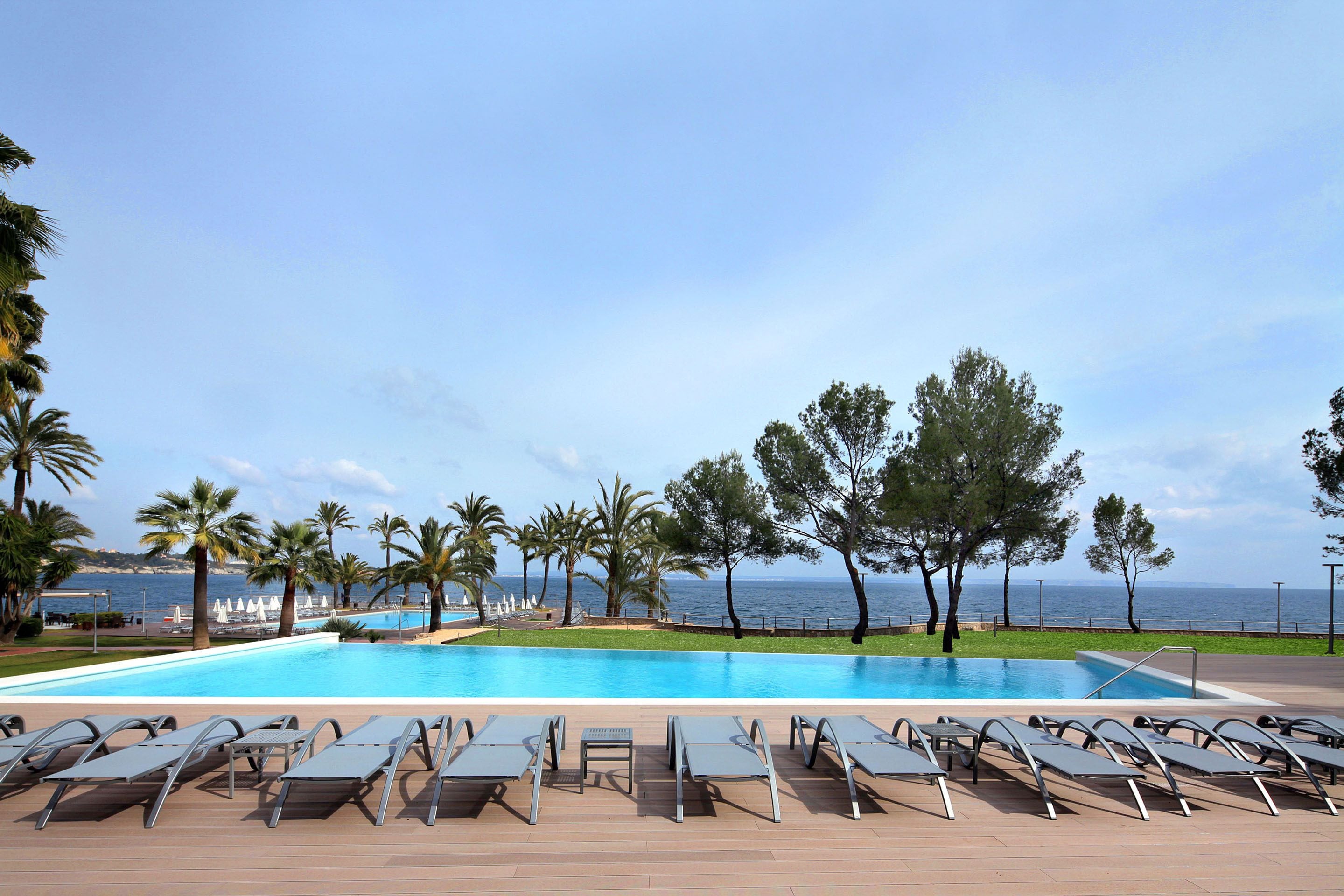 A pool area with lounge chairs and a view of the sea.