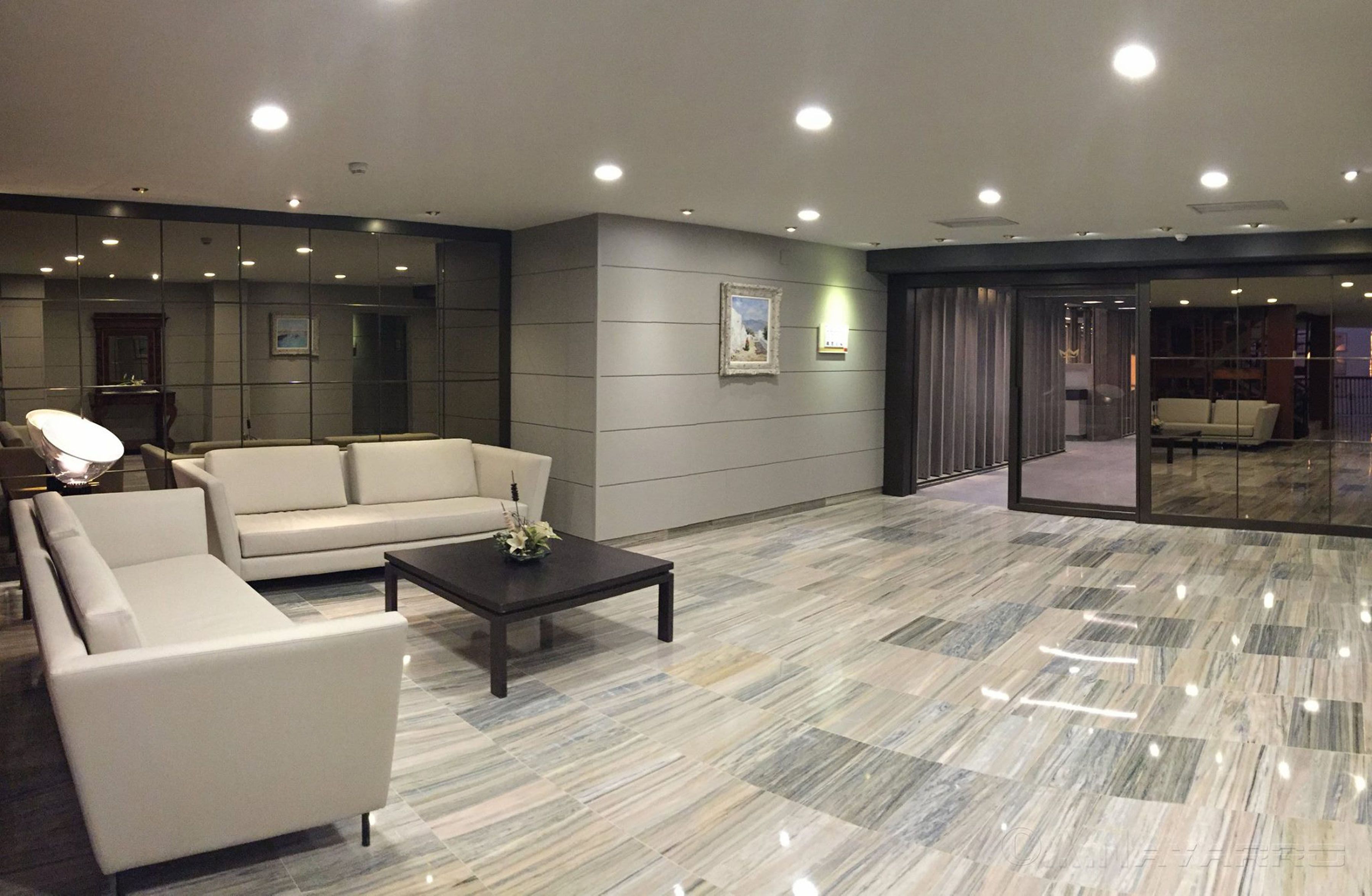 Un hall d’hôtel moderne avec un canapé, une table basse et un grand miroir.