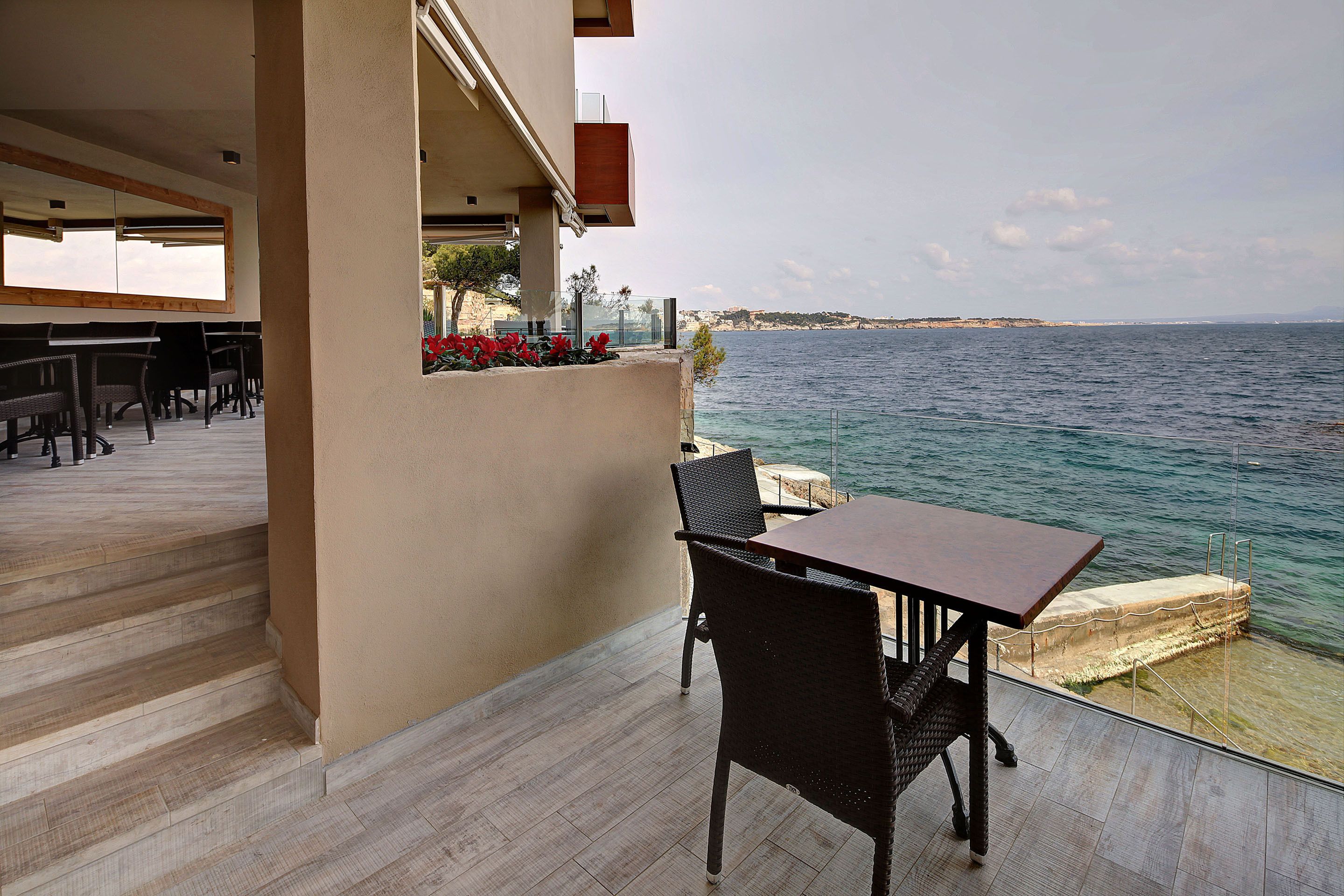 A balcony with a table and chairs overlooking a body of water.