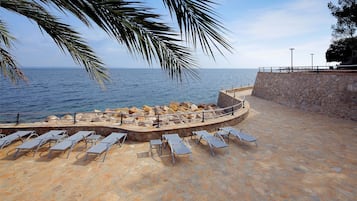 A stone deck with sun loungers overlooking the sea.