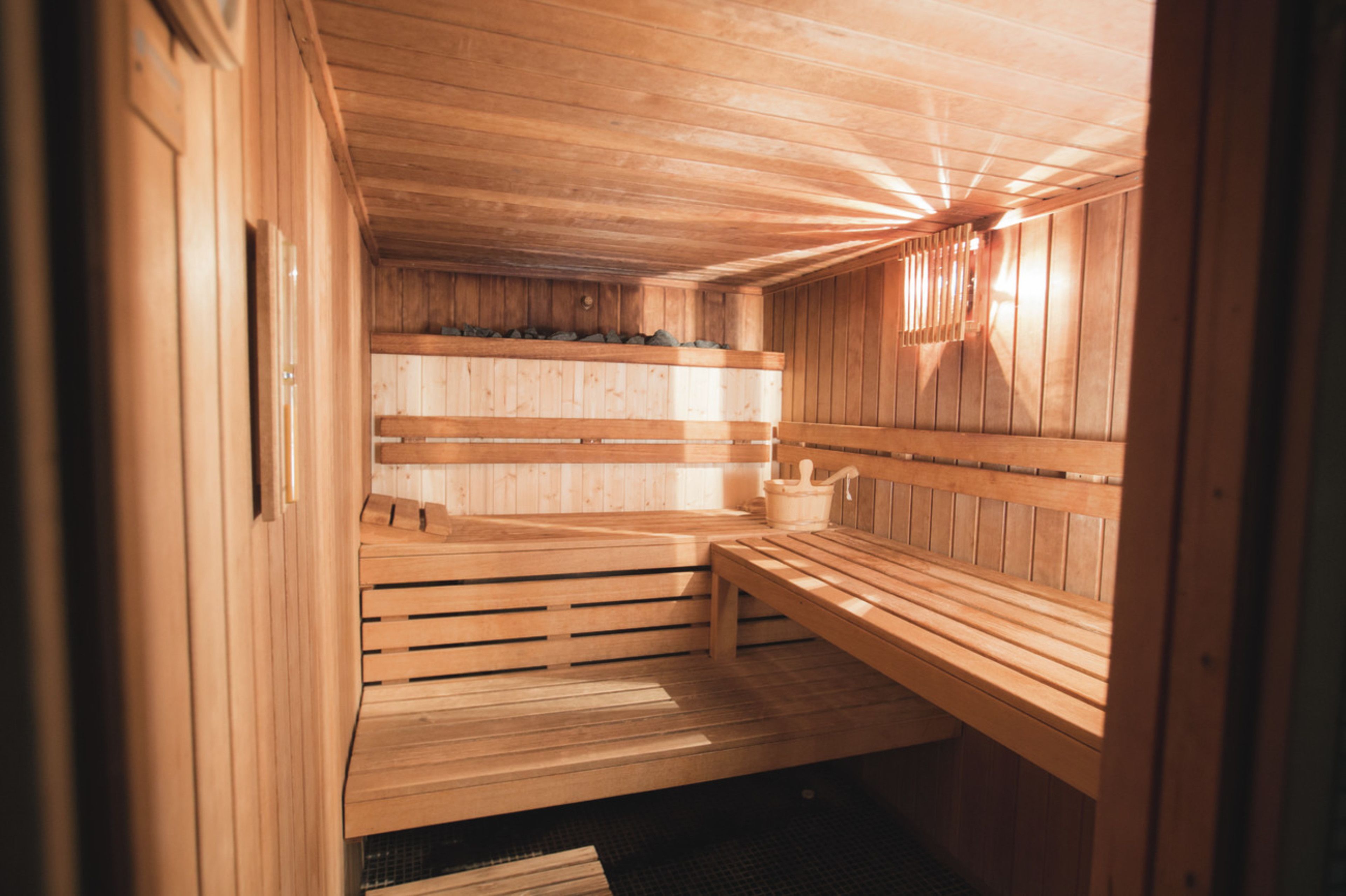 A wooden sauna with benches and a bench with a bucket.