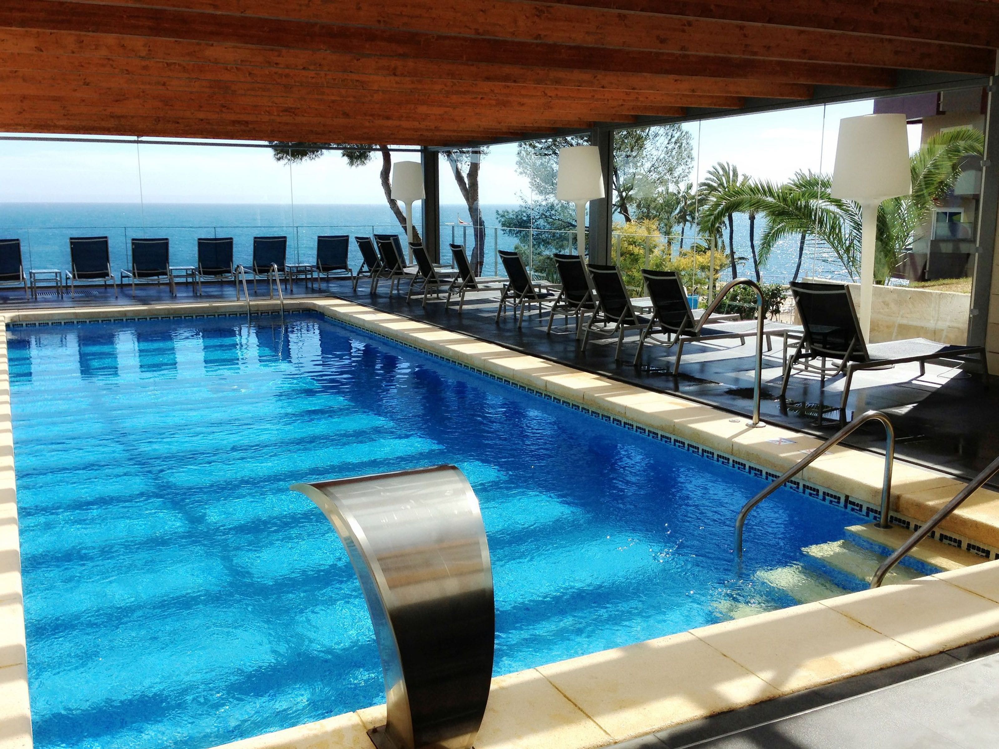 Una piscina con sillas de descanso y vista al océano.