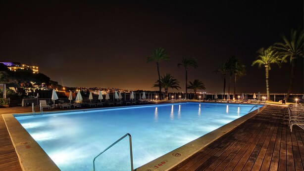 A swimming pool with a wooden deck, lounge chairs, and umbrellas. - Palace Bonanza Playa Resort & SPA by Olivia Hotels Collection (Calvia)