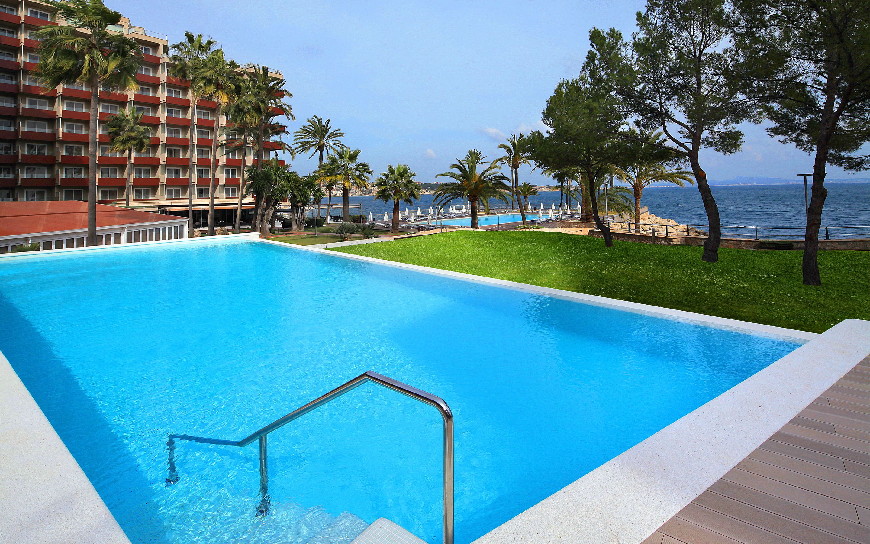 Una piscina con vista despejada al océano y un hotel al fondo.