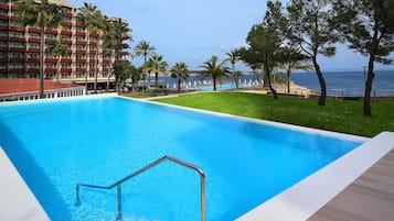Una piscina con vista despejada al océano y un hotel al fondo.