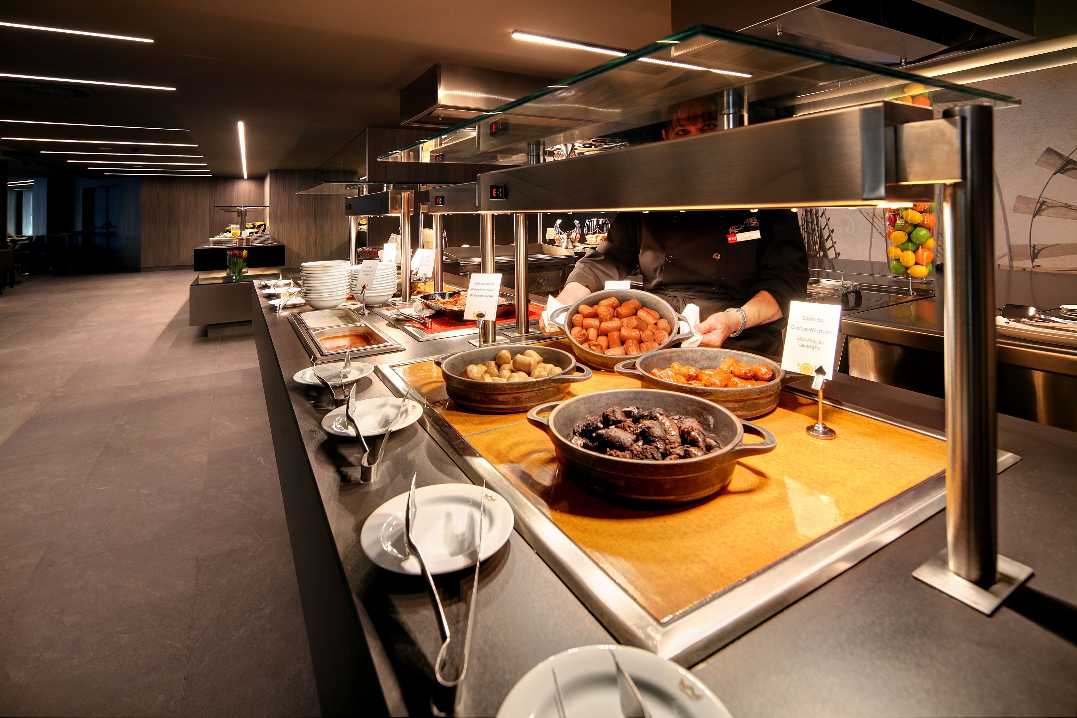 A buffet with various food items and a person serving.