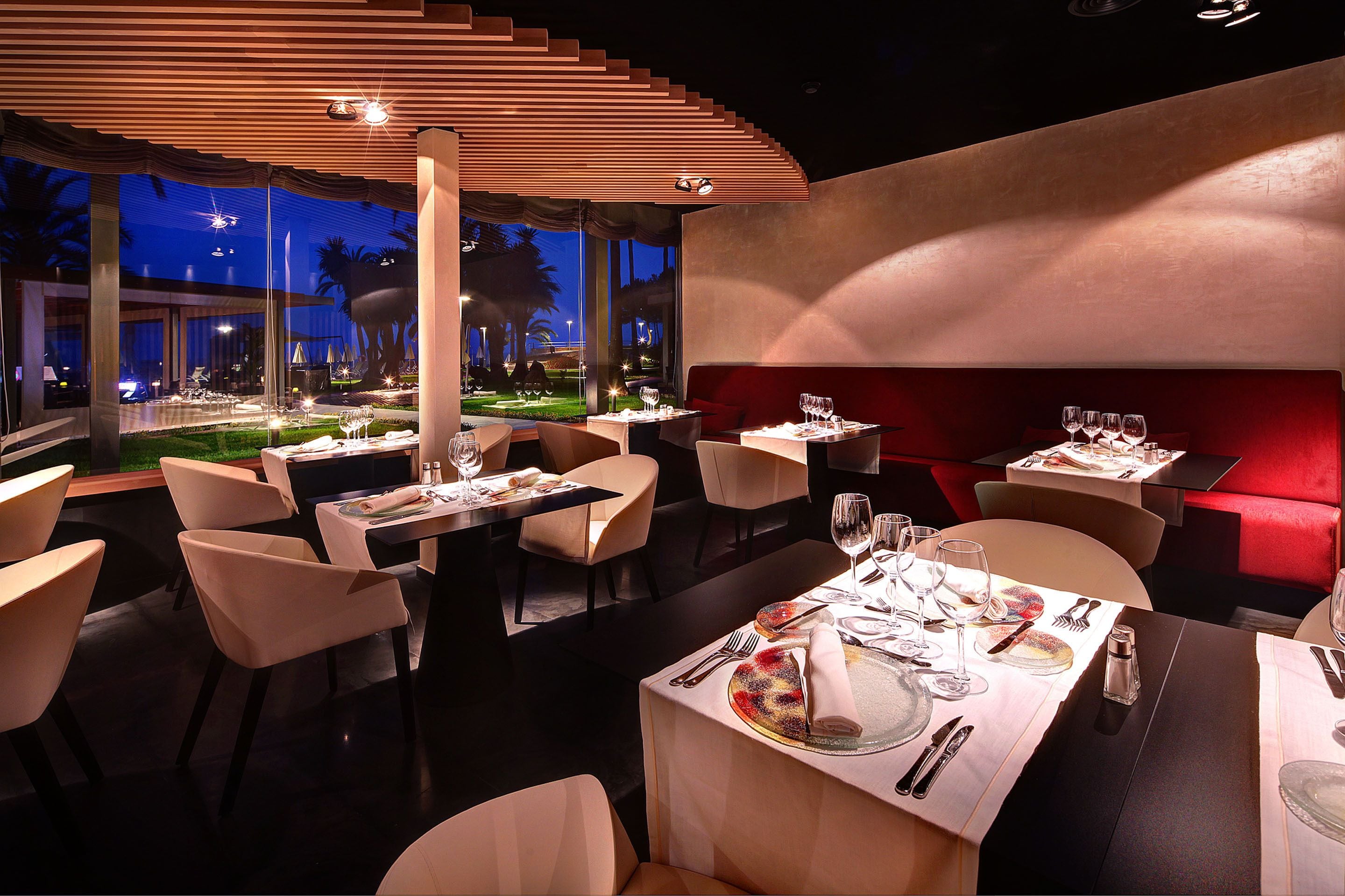 A restaurant with tables set for dining, a view of the outdoors, and a modern interior design.