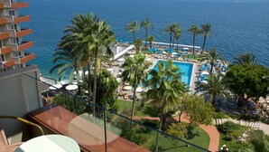 A resort with a pool, palm trees, and a view of the sea.