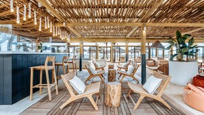 An outdoor seating area with wooden furniture and a thatched roof.