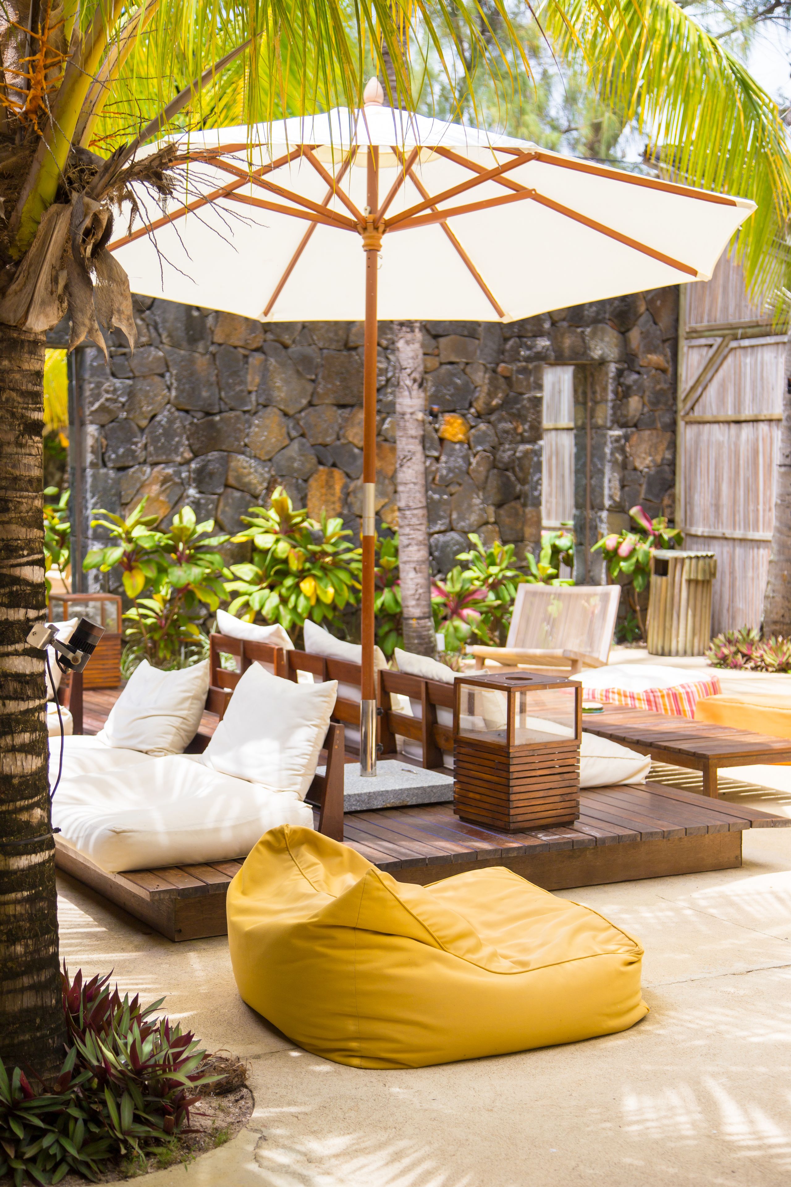 A patio with a stone wall, wooden furniture, and a yellow bean bag.