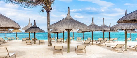 On the beach, white sand, sun loungers, beach umbrellas