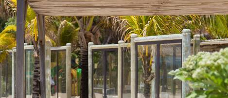 Un paseo marítimo en la playa con un banco de madera y barandillas de vidrio.