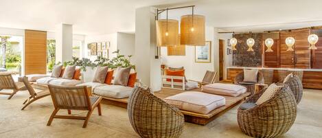 A spacious living area with a large sofa set, wicker chairs, and a dining table.