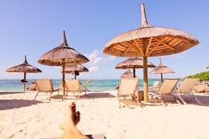 Am Strand, weißer Sandstrand, Liegestühle, Sonnenschirme